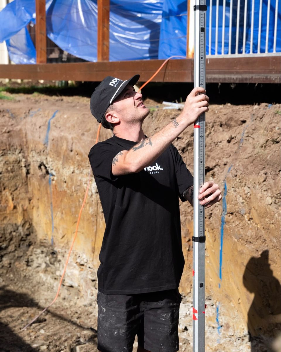 Lachie McKinlay, licensed builder and construction director at Nook Pools & Spas, checking levels on a pool excavation